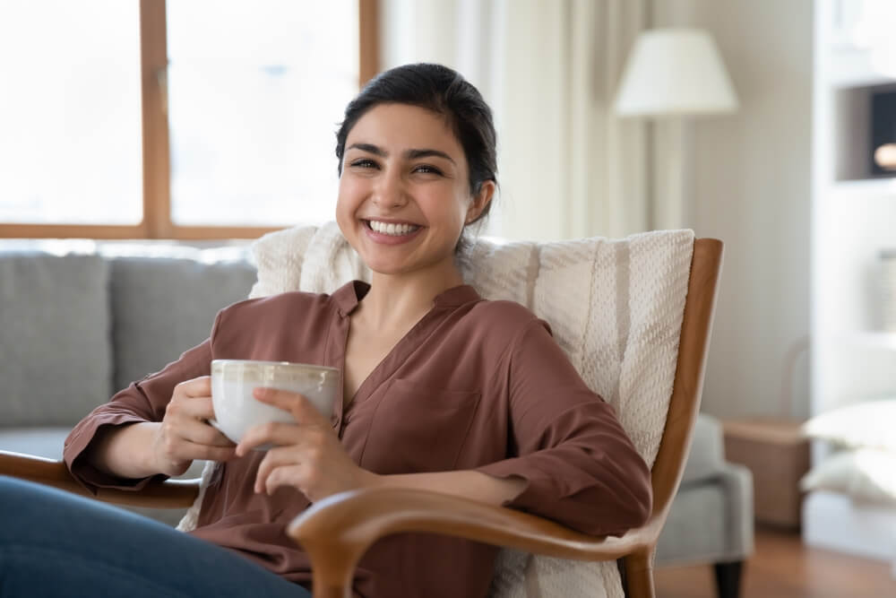 smiling beautiful indian ethnicity woman resting in cozy armchair